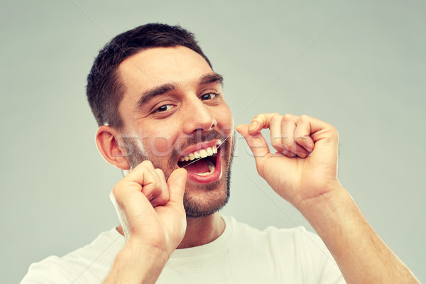 man with dental floss cleaning teeth over gray Stock photo © dolgachov
