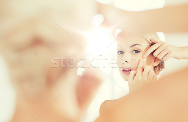 woman squeezing pimple at bathroom mirror Stock photo © dolgachov