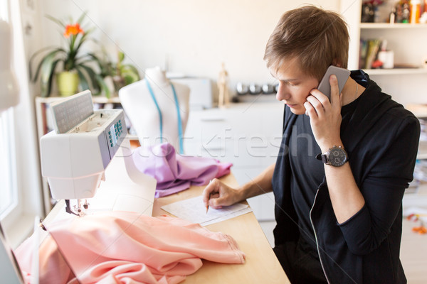 fashion designer calling on smartphone at studio Stock photo © dolgachov