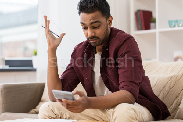 confused man with calculator at home Stock photo © dolgachov