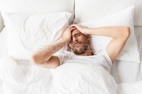Stock photo: man in bed at home suffering from headache