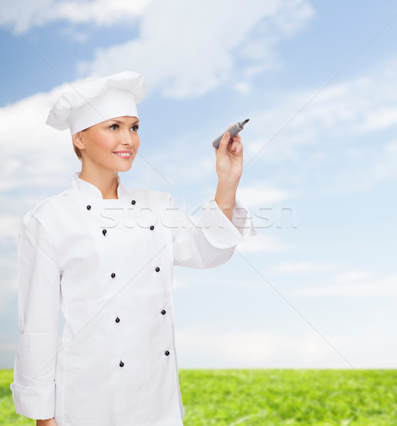 smiling female chef writing something on air Stock photo © dolgachov