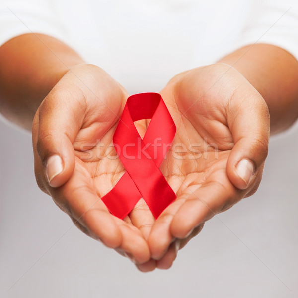 hands holding red AIDS awareness ribbon Stock photo © dolgachov