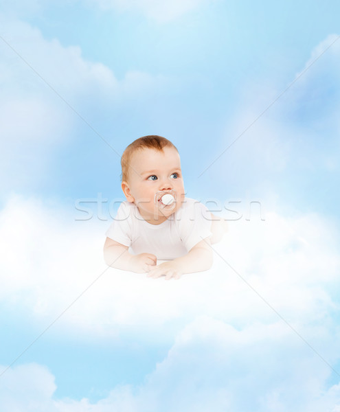 Stock photo: smiling baby lying on cloud with dummy in mouth
