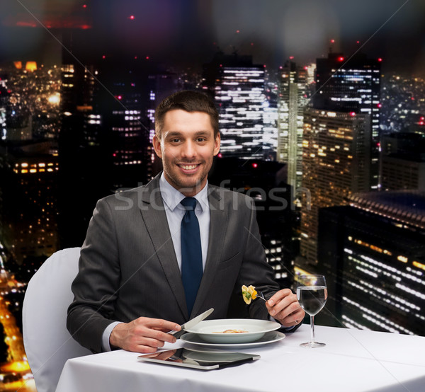 smiling man with tablet pc eating main course Stock photo © dolgachov