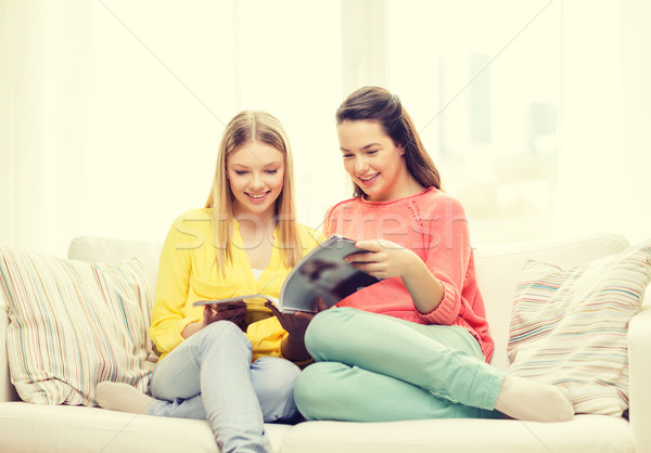 Stock photo: two girlfriends reading magazine at home