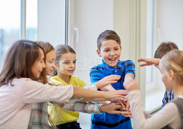 group of smiling school kids putting hands on top Stock photo © dolgachov
