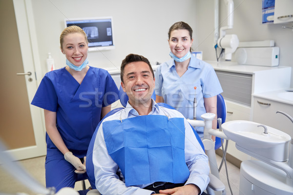 happy female dentists with man patient at clinic Stock photo © dolgachov