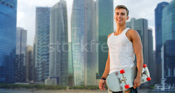 smiling man with skateboard over singapore city Stock photo © dolgachov