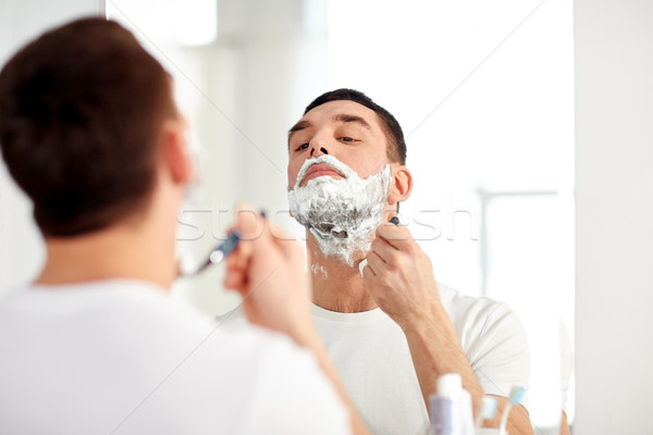 man shaving beard with razor blade at bathroom Stock photo © dolgachov