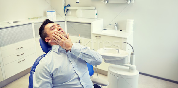 Stock photo: man having toothache and sitting on dental chair