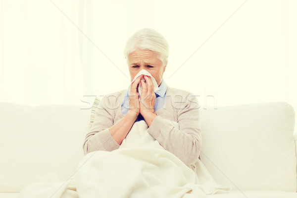 sick senior woman blowing nose to paper napkin Stock photo © dolgachov