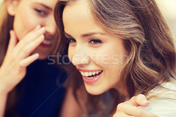 Stock photo: smiling young women gossiping and whispering