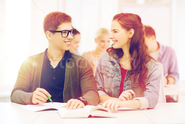 Stock photo: two teenagers with notebooks and book at school