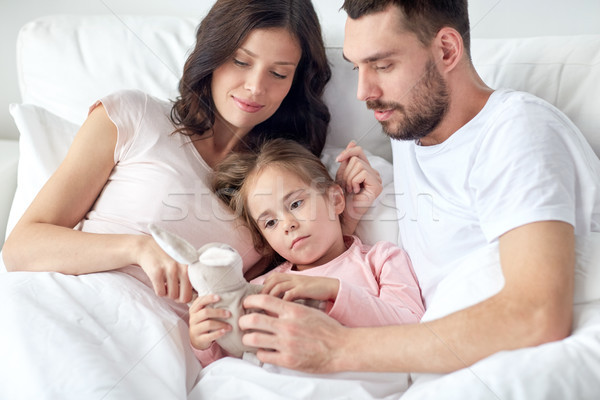happy child with toy and parents in bed at home Stock photo © dolgachov