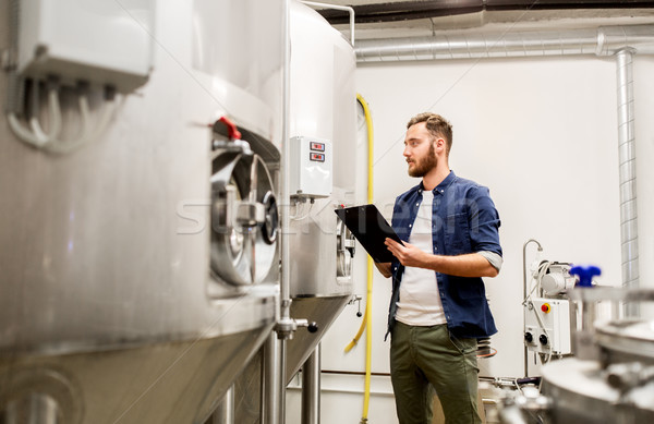 man with clipboard at craft brewery or beer plant Stock photo © dolgachov