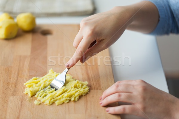 hand with fork making mashed potato on board Stock photo © dolgachov