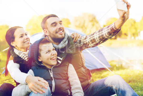 family with smartphone taking selfie at campsite Stock photo © dolgachov