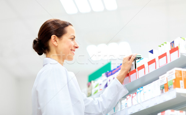 happy female apothecary with drug at pharmacy Stock photo © dolgachov