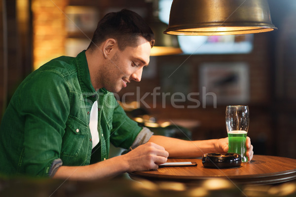 man with smartphone and green beer texting at bar Stock photo © dolgachov