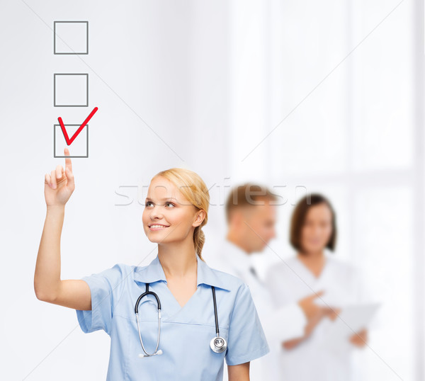doctor or nurse drawning checkmark into checkbox Stock photo © dolgachov