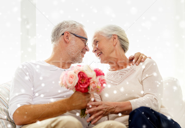 Stock photo: happy senior couple with bunch of flowers at home