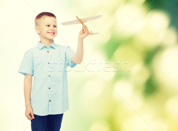 Stock photo: smiling little boy holding a wooden airplane model