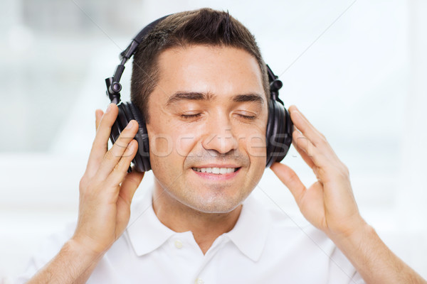 happy man in headphones listening to music at home Stock photo © dolgachov