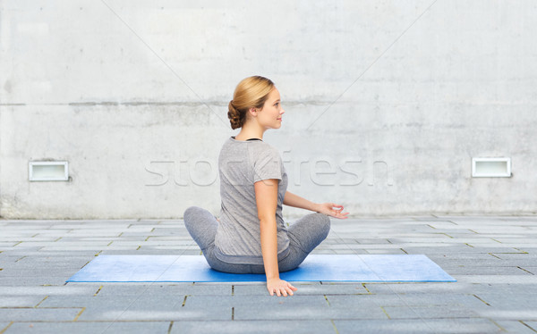 woman making yoga in twist pose on mat outdoors Stock photo © dolgachov