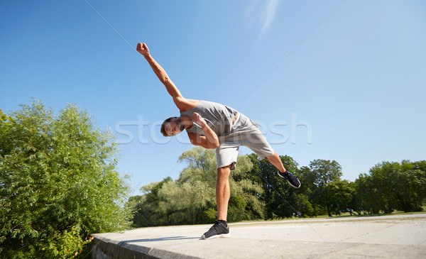 sporty young man jumping in summer park Stock photo © dolgachov