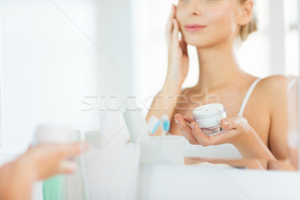 close up of woman applying face cream at bathroom Stock photo © dolgachov