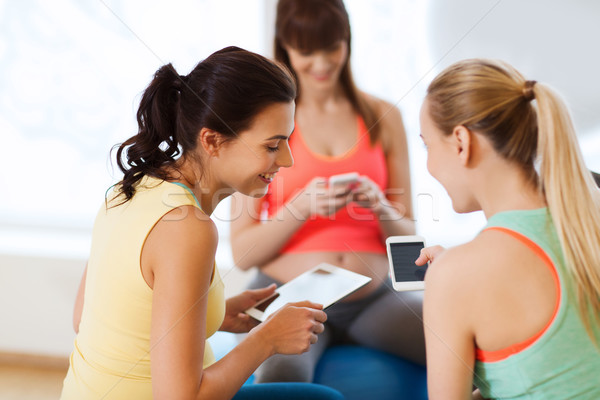 Stock photo: happy pregnant women with gadgets in gym