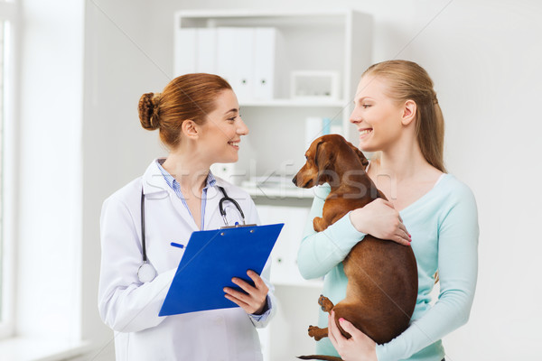 happy woman with dog and doctor at vet clinic Stock photo © dolgachov