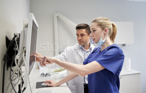 dentists with x-ray on monitor at dental clinic Stock photo © dolgachov