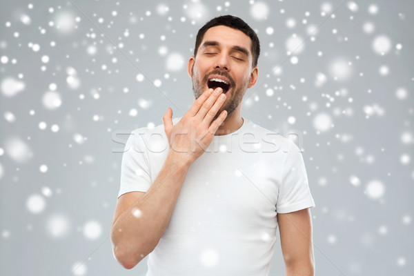 yawning man over snow background Stock photo © dolgachov