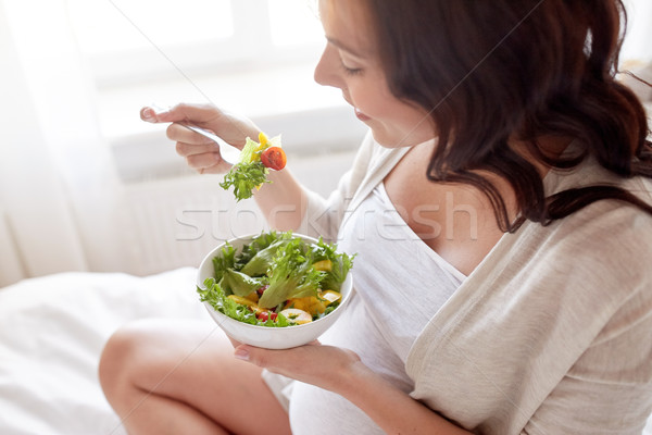 Stock photo: close up of pregnant woman eating salad at home