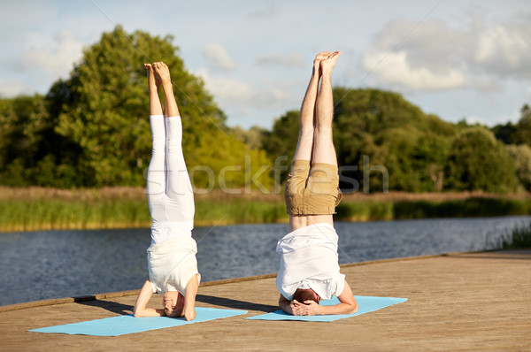 couple making yoga headstand on mat outdoors Stock photo © dolgachov