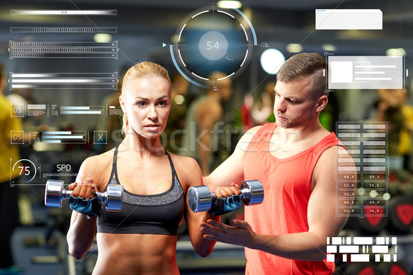 young couple with dumbbells flexing muscles in gym Stock photo © dolgachov