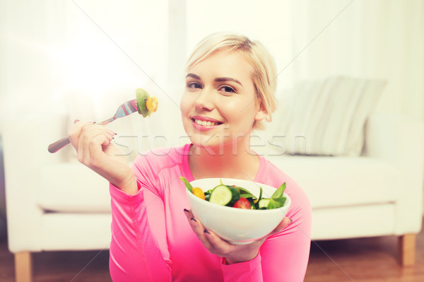 Souriant jeune femme manger salade maison [[stock_photo]] © dolgachov