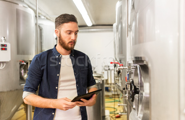 man with tablet pc at craft brewery or beer plant Stock photo © dolgachov