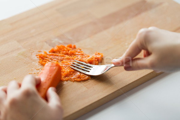 hand with fork making mashed carrot on board Stock photo © dolgachov