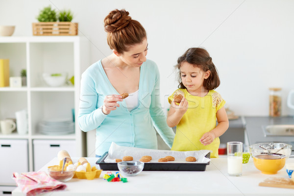 happy mother and daughter eating cookies at home Stock photo © dolgachov