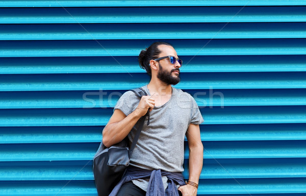 man in sunglasses with bag standing at street wall Stock photo © dolgachov