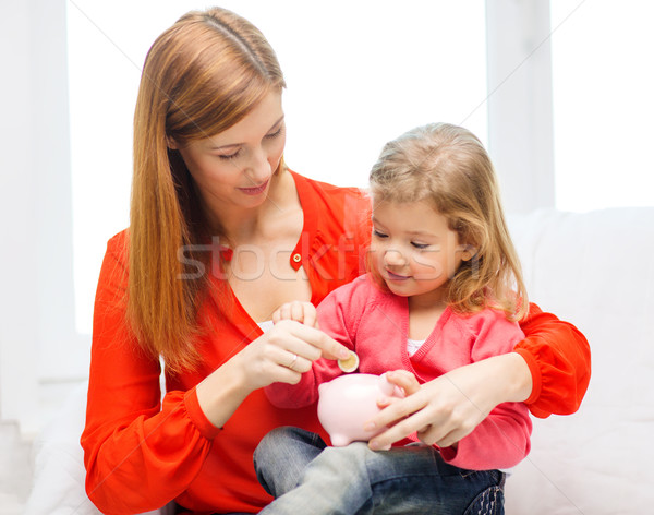 happy mother and daughter with small piggy bank Stock photo © dolgachov