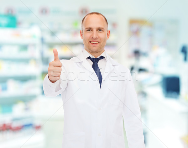 smiling pharmacist showing thumbs up at drugstore Stock photo © dolgachov