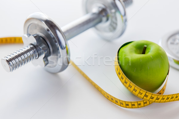 close up of dumbbell and apple with measuring tape Stock photo © dolgachov