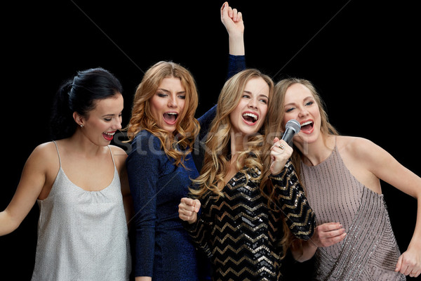happy young women with microphone singing karaoke Stock photo © dolgachov