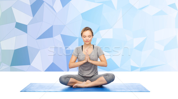 Stock photo: woman making yoga meditation in lotus pose on mat
