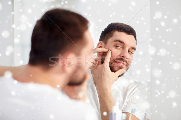 man squeezing pimple at bathroom mirror Stock photo © dolgachov