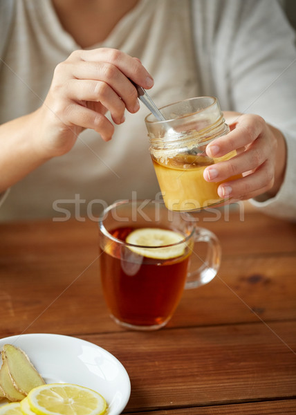 close up of woman adding honey to tea with lemon Stock photo © dolgachov